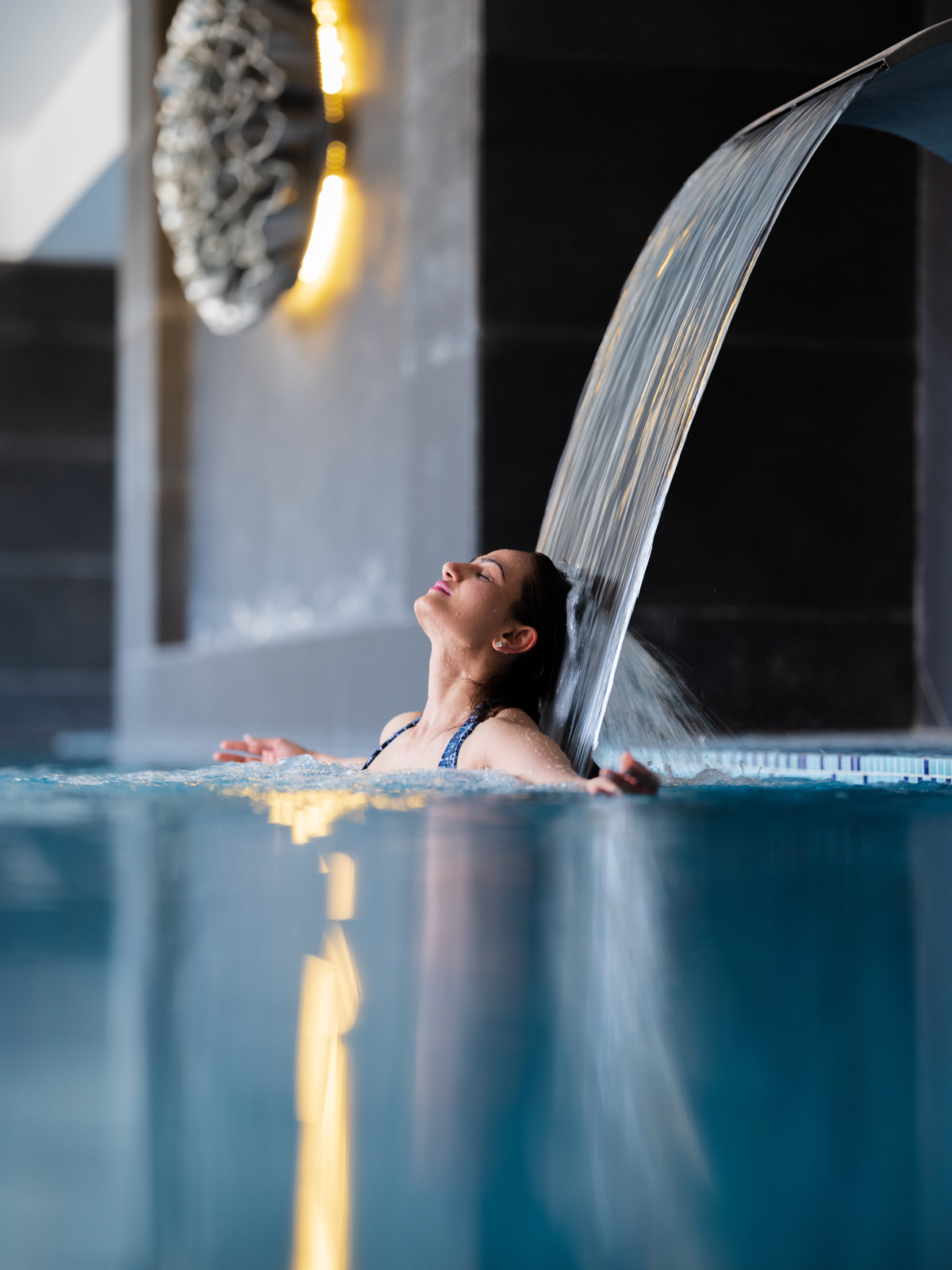A spacious and well-appointed hotel room featuring a king-sized bed, light yellow seating, and coastal-inspired artwork with a sophisticated color palette and wooden floors.