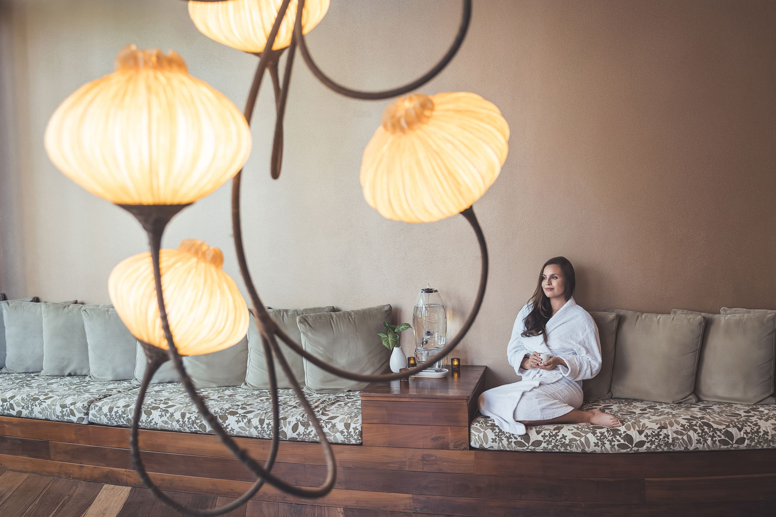 A serene bathroom interior featuring a modern white bathtub next to large glass windows overlooking a lush green forest with a hanging chair and wooden deck.