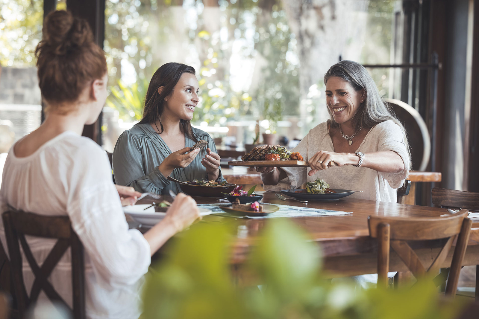 A woman in a white bathrobe sits on a cushioned bench near elegant sculptural lighting, creating a calm and luxurious wellness environment.